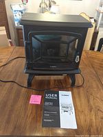 Front view of Turbro electric stove on table with user manual and sticky note