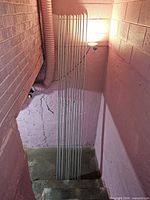 Twelve conduit pipes standing vertically against wall
