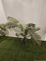 Full view of artificial palm plant against pegboard backdrop