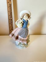 Front view of Lladro porcelain girl figurine beside ruler for scale
