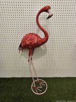 Full view of metal flamingo statue on base