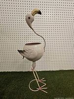 Full view of metal flamingo planter standing on grass backdrop