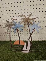 Full view of metal tropical scene wall hanging showing palm trees, sailboat, sun and birds