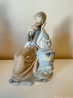 Front view of Nao figurine showing girl, basket of grapes, tree trunk