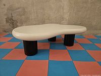 Angled view showing cream organic top and three black cylindrical legs