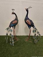 Full view of both painted metal peacock sculptures