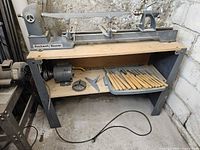 Full view of lathe on stand with motor and chisel tray