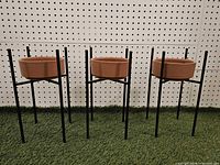 Three clay planters on metal stands, front view
