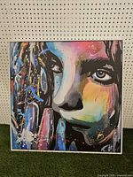 front view of colourful abstract portrait canvas in white frame