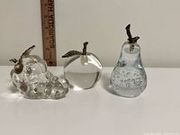 Front view of three crystal fruit paperweights