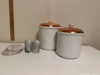 group shot of two ceramic canisters with copper lids, marble shakers and stacked marble coasters