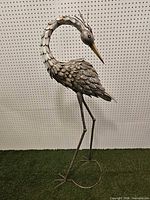 Full view of tall metal bird sculpture on grass backdrop