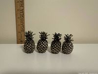 front view of four silver-plated pineapple place card holders