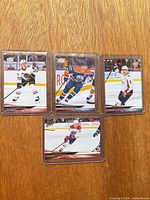 Group shot of all four sleeved and top-loaded cards on wooden surface