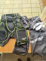 Full view of Alkali padded shorts and separate overpant shell on table