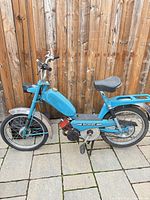 Full left side view of blue Batavus moped showing overall condition, wheels, seat, luggage rack