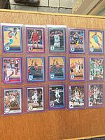 All fifteen Panini Hoops purple parallel cards in protective sleeves laid out on board