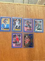 All six sleeved Panini basketball cards on wooden surface