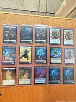 Fifteen toploaders displaying front side of foil tokens on tabletop