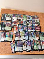 Wide view of roughly 100 foil MTG cards spread on surface