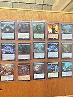 Fifteen sleeved extended art MTG cards displayed on wood surface