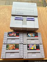SNES console with four game cartridges displayed on wood surface