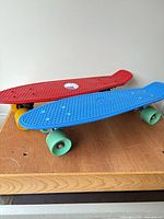 Top view of both plastic cruiser skateboards showing red and blue decks