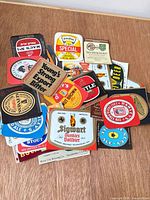 Overhead view of pile of small beer labels displaying various brewery logos