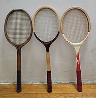 Front view of three wooden racquets standing upright