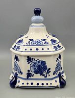 Front view of square Delft bowl with lid showing blue floral motifs and finial