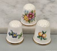 Front view of three floral bone china thimbles
