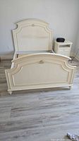 Full view of assembled cream bed frame showing headboard, footboard and side rails