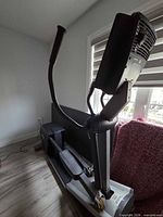 Full side view of elliptical showing drive housing, foot pedals and upright handles