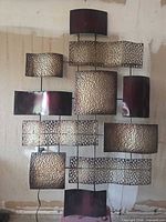 Full view of metal sculpture showing all staggered rectangular panels and power cord