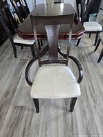 Front view of dark wood armchair with cream cushioned seat