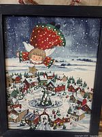 Front view of framed Christmas print showing angel over village