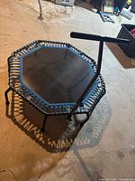 Full view of octagonal trampoline showing handlebar, blue bungees, legs