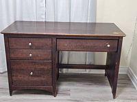 Full front view of dark wood desk showing drawers and leg space