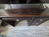 Front view showing entire desk, drawers, open cubby, metal pulls, wear on surface