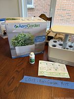 Box, hydroponic unit, plant food bottle and manual on table