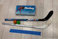 Overview of two mini sticks, two balls and NHL Hockey card game box
