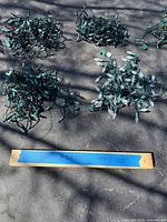 Overview of several bundled strings of green-wired Christmas lights on pavement