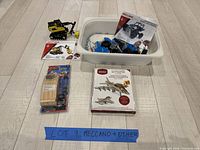 Overview of all kits including assembled Meccano vehicle, unassembled parts in bin, jet fighter box, pine racer pack