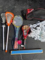 Full view of badminton set, lacrosse sticks, paddle racket, net, duffle bag