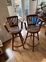 Two matching oak swivel bar stools full view