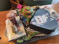 Assorted cat items arranged on tray including book, tins, figurine, boards, heart box