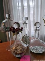 Group shot showing all glass pieces: three decanters with stoppers, cloche over compote dish, fillers inside