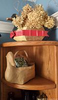 Wooden and paper-mâché duck containers on shelf with dried hydrangea and one book visible