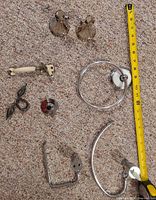 All eight hardware pieces laid out on carpet beside measuring tape