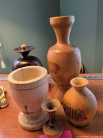Group of five wooden vases displayed upright on table